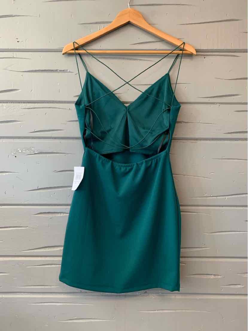Green sleeveless dress with spaghetti straps and crisscross back detail hanging on wooden hanger.