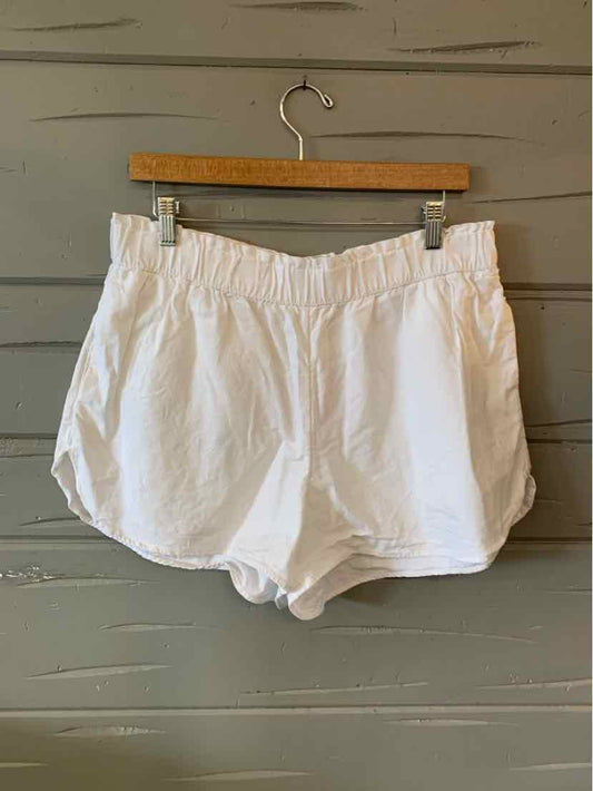 White elastic waist casual shorts with curved hem and lightweight fabric hanging on wooden hanger.