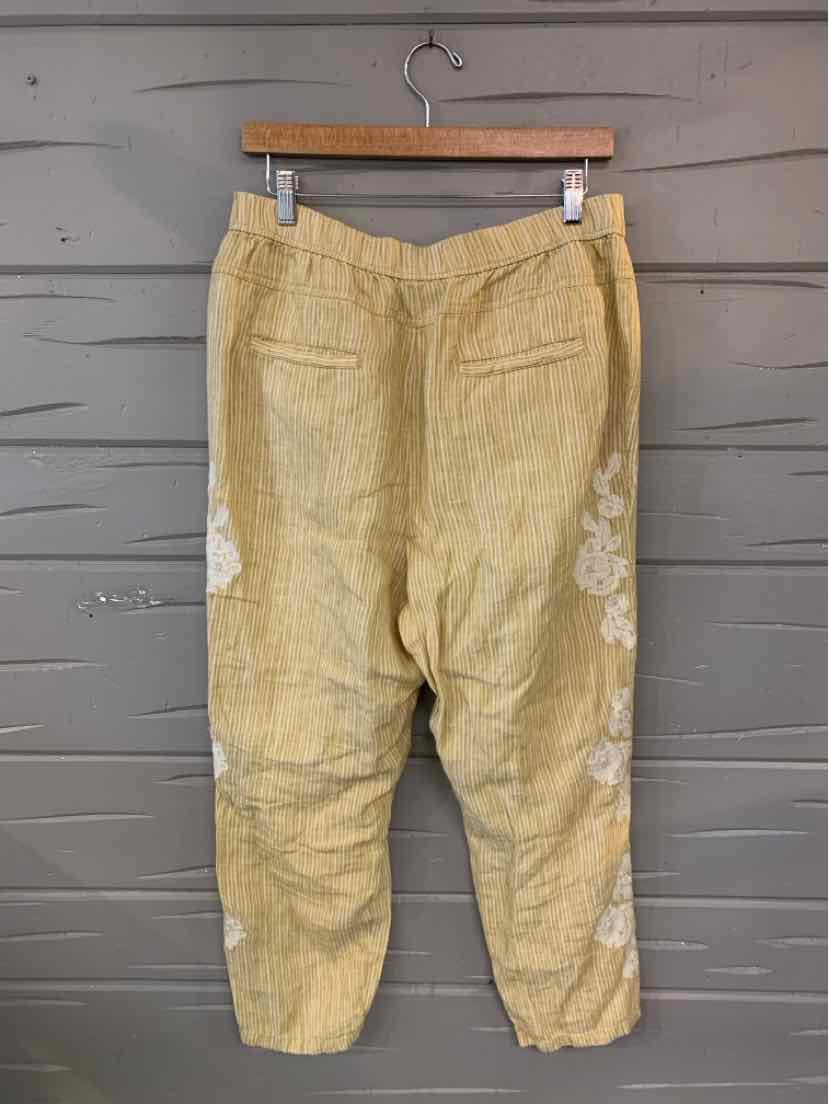 Yellow cropped pants with white floral embroidery, elastic waistband, and back patch pockets.