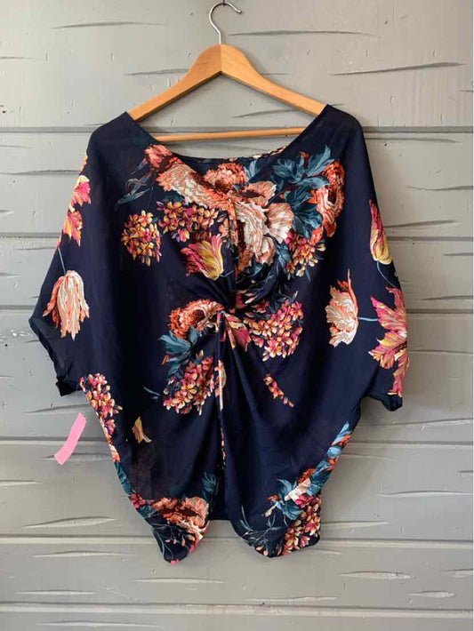 Navy blue floral blouse with ruched front and three-quarter sleeves on wooden hanger.