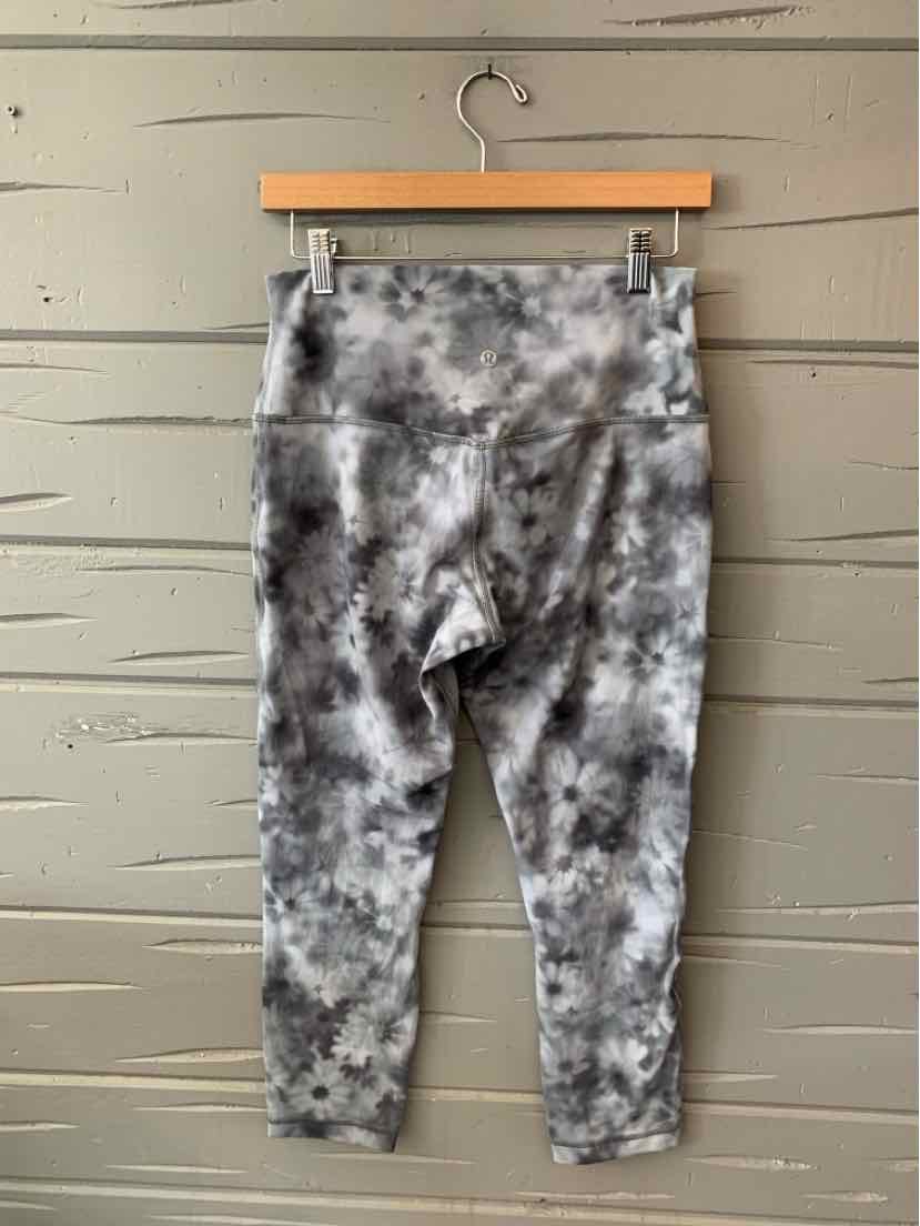 Gray and black tie-dye patterned high-waisted leggings with a cropped ankle length hanging on a wooden hanger.