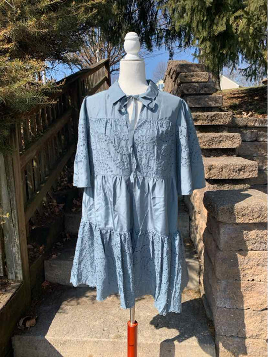 Light blue eyelet dress with tiered skirt, half sleeves, and front tie neckline on mannequin outdoors.