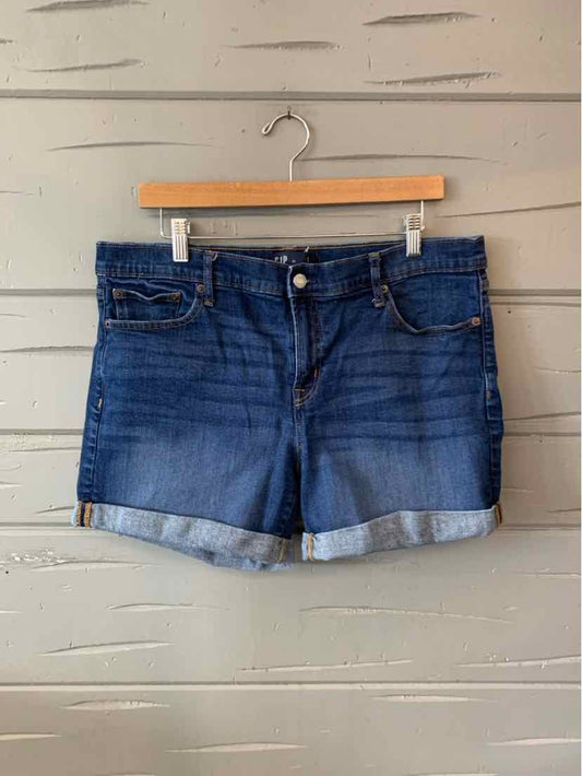 Dark blue denim shorts with rolled cuffs, front button, and pockets on a wooden hanger.
