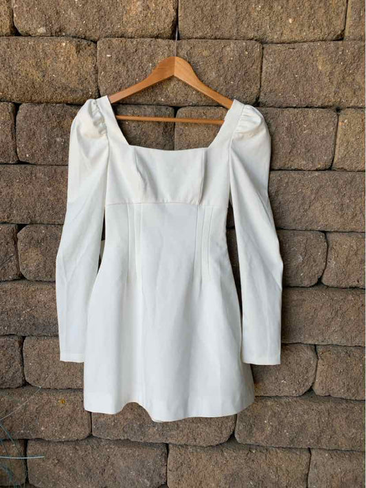 White mini dress with long puffed sleeves and square neckline, fitted waist.