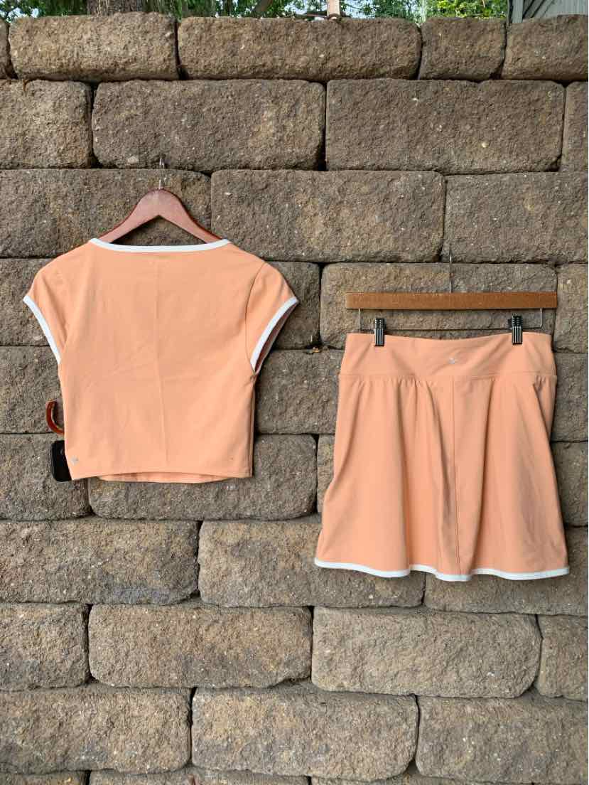 Peach short-sleeve active crop top and matching shorts set with white trim, lightweight fabric.