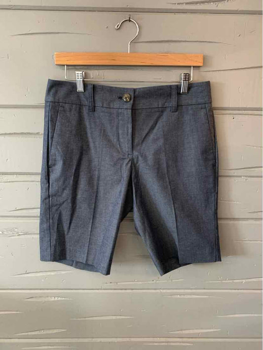 Gray knee-length tailored shorts with front button and zip closure on wooden hanger.