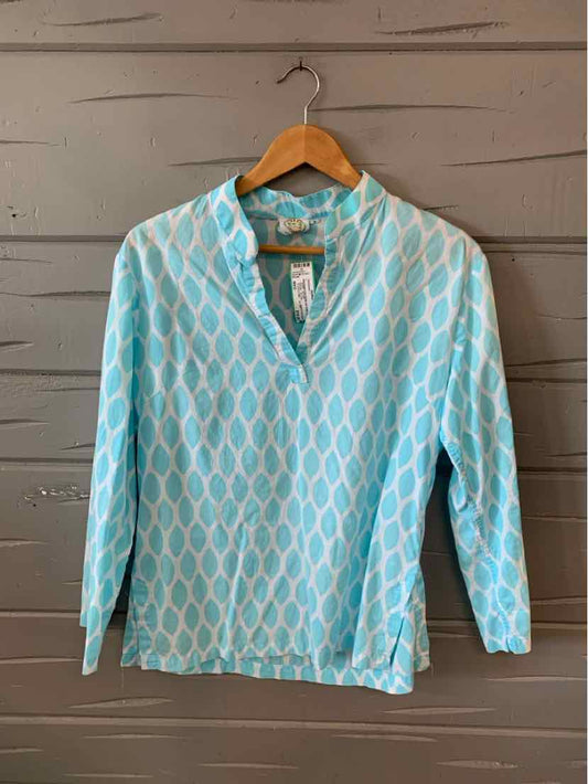 Light blue long-sleeve shirt with white geometric pattern and V-neck collar on wooden hanger.