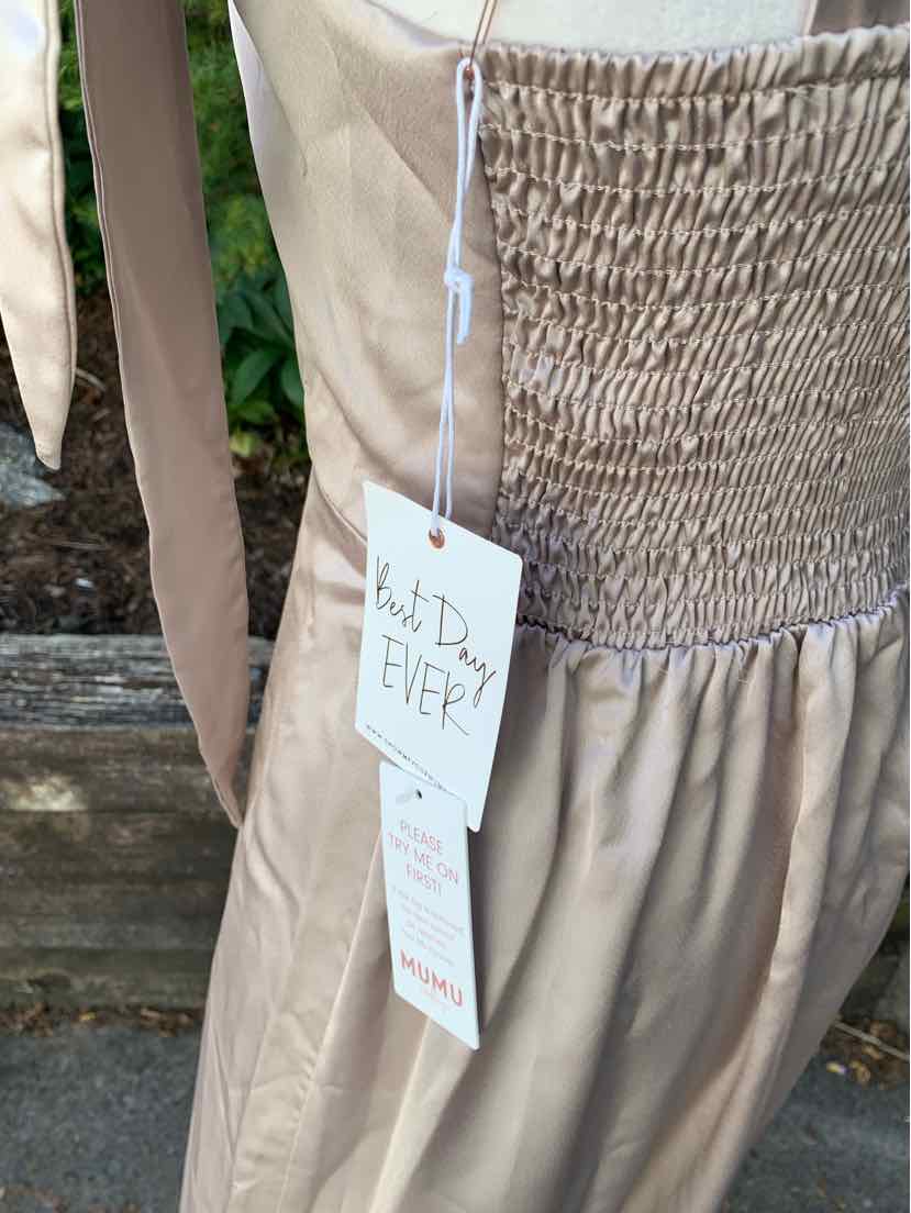 Beige sleeveless dress with smocked bodice and flowy skirt in lightweight fabric.