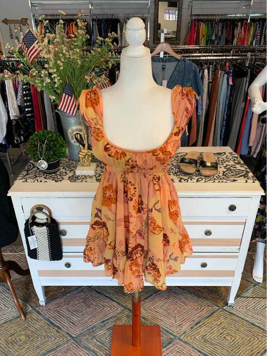 Orange floral short dress with ruffled cap sleeves and a fitted waist on a mannequin.