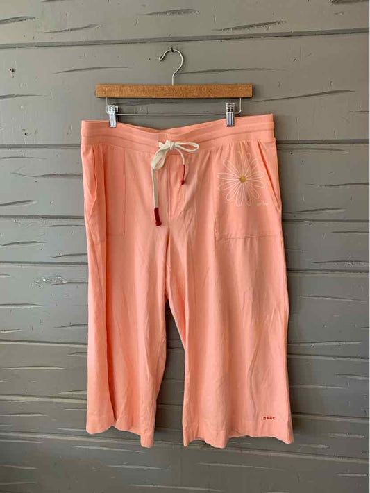 Coral pink cropped wide-leg pants with drawstring waist and side pockets on wooden hanger.
