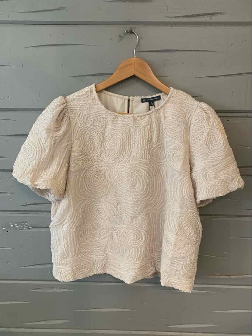 Beige textured short-sleeve blouse with puffed sleeves and round neckline hanging on wooden hanger.