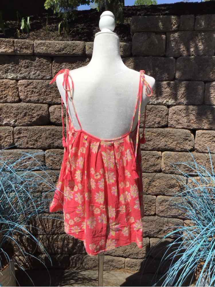 Coral pink floral sleeveless top with thin tie straps and low back on white mannequin.
