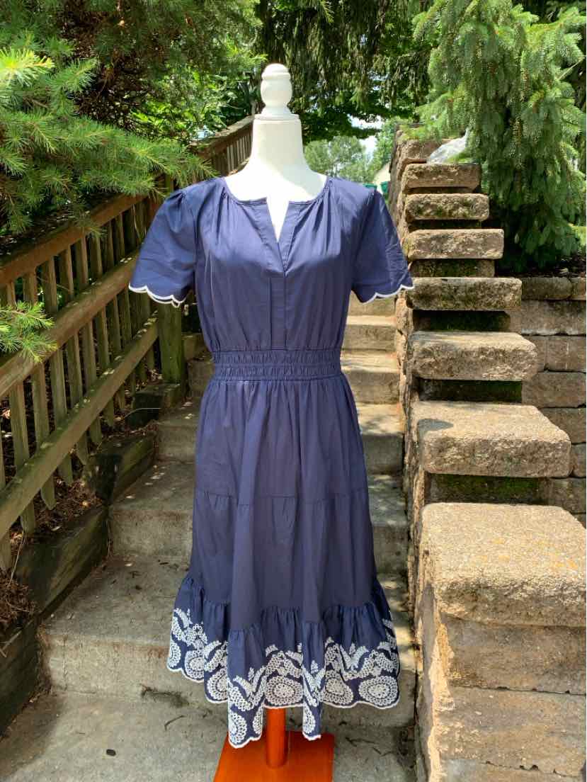 Navy blue dress with puff sleeves, fitted waist, V-neckline, and white eyelet floral border at hem.