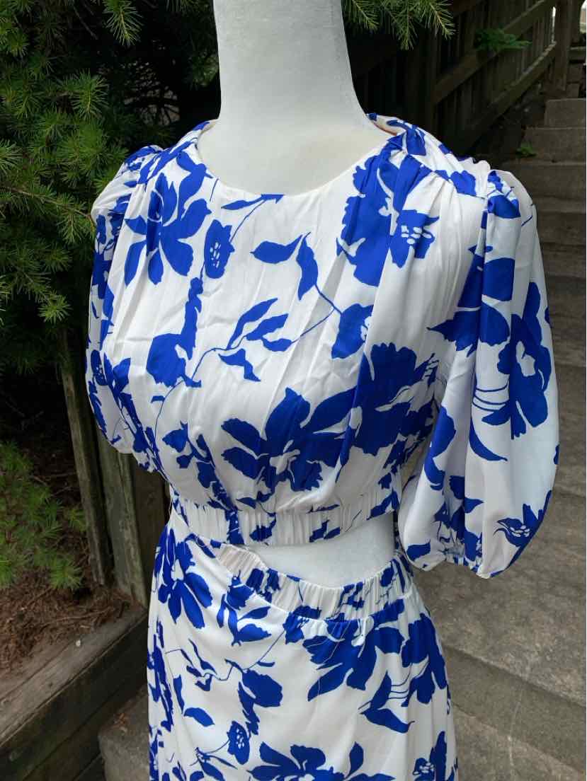 White dress with bold blue floral print, puffed short sleeves, and fitted waist.