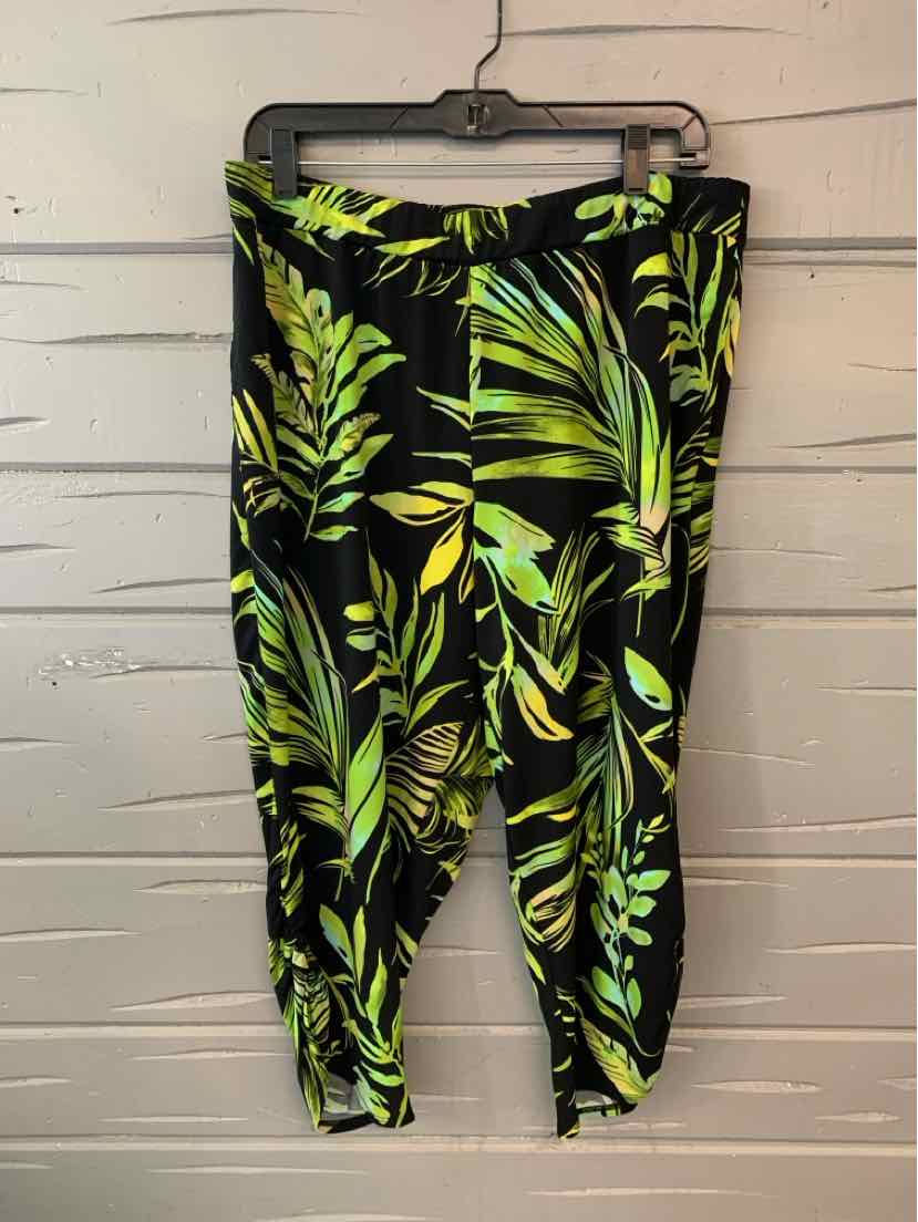 Black leggings with vibrant green tropical leaf print, size large, hanging on black hanger.