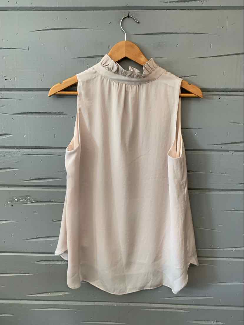 Sleeveless nude blouse with high ruffled neckline and flowy lightweight fabric hanging on wooden hanger.