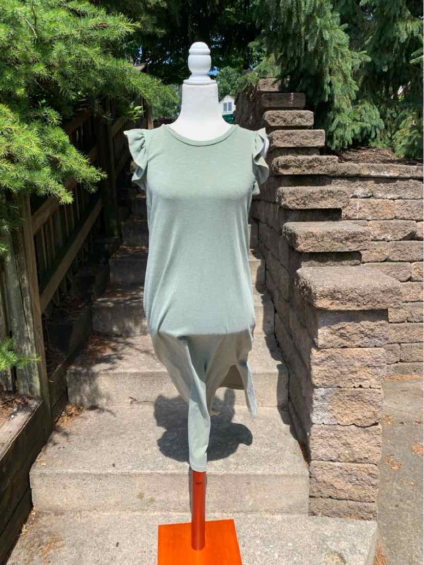 Light sage green sleeveless dress with ruffled shoulder details on mannequin outdoors.