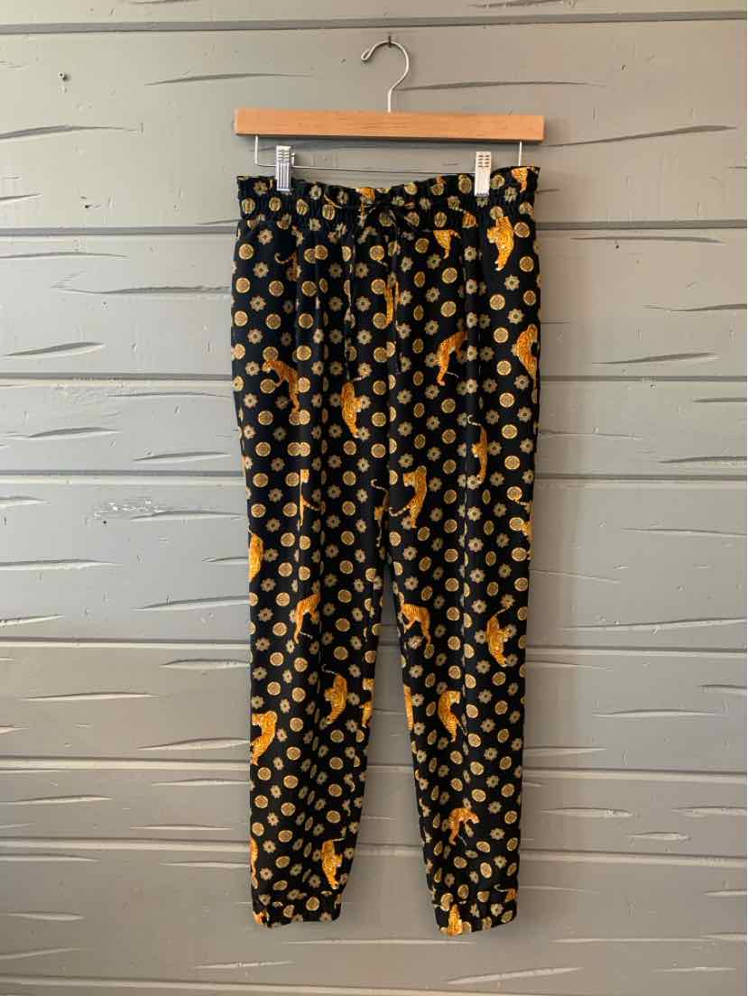 Black tapered pants with orange tiger and polka dot print, elastic waistband, and ankle cuffs.