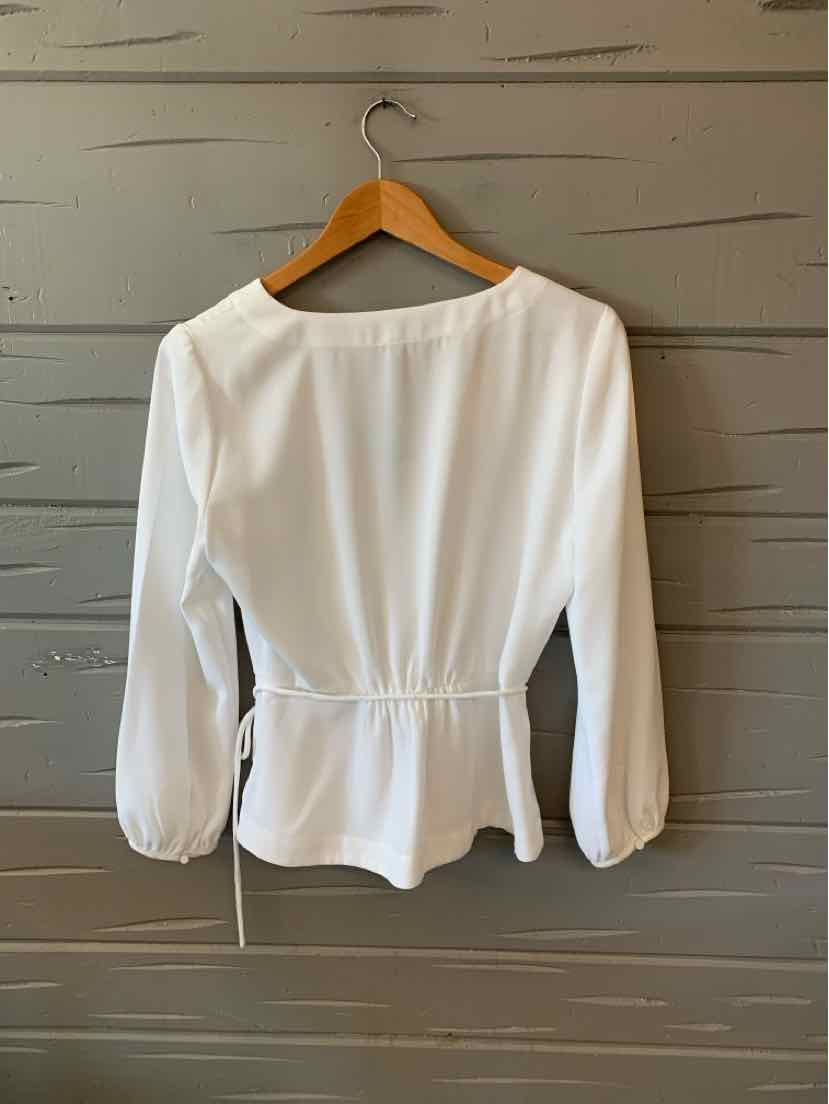 White long-sleeve blouse with cinched waist and boat neckline on wooden hanger.
