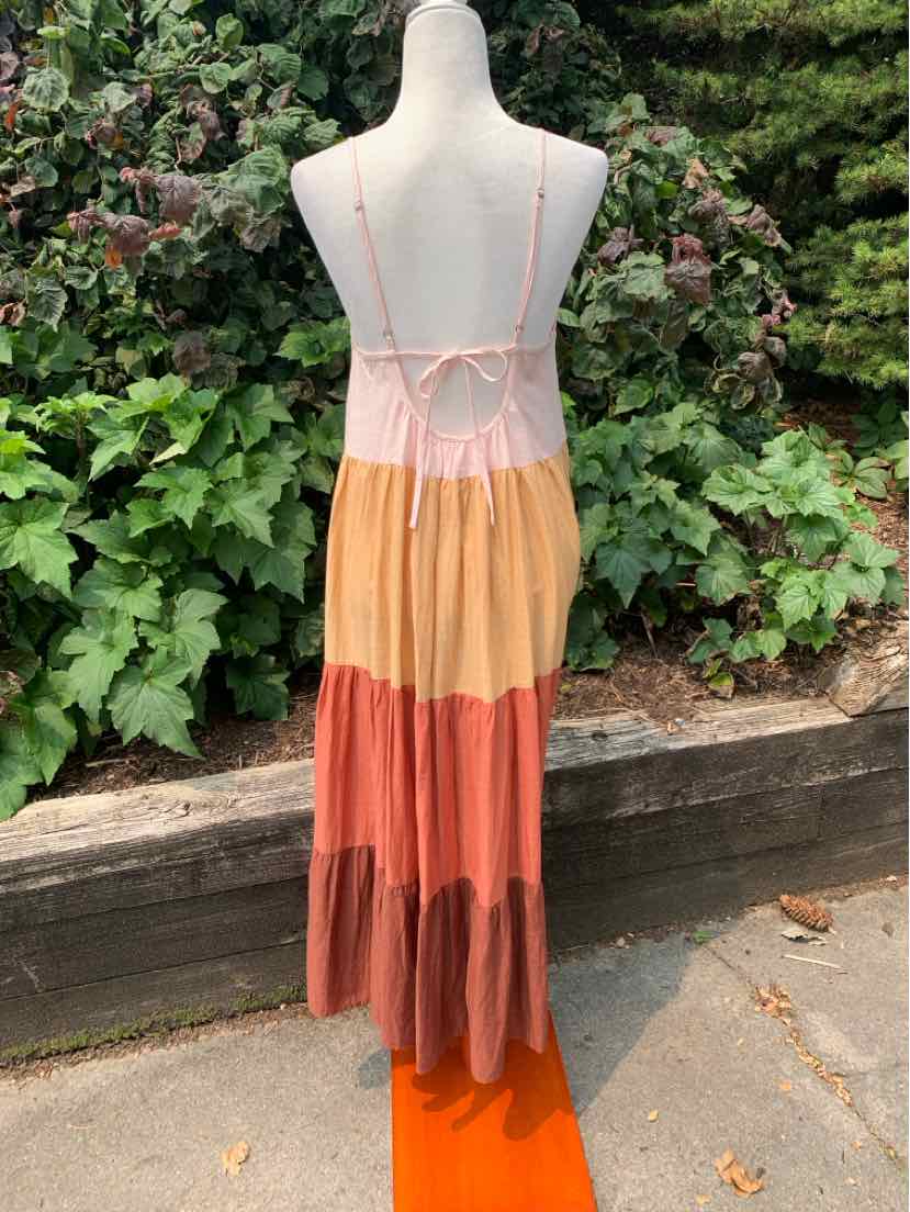 Sleeveless color block maxi dress with thin straps and tiered skirt in peach, orange, and rust tones.
