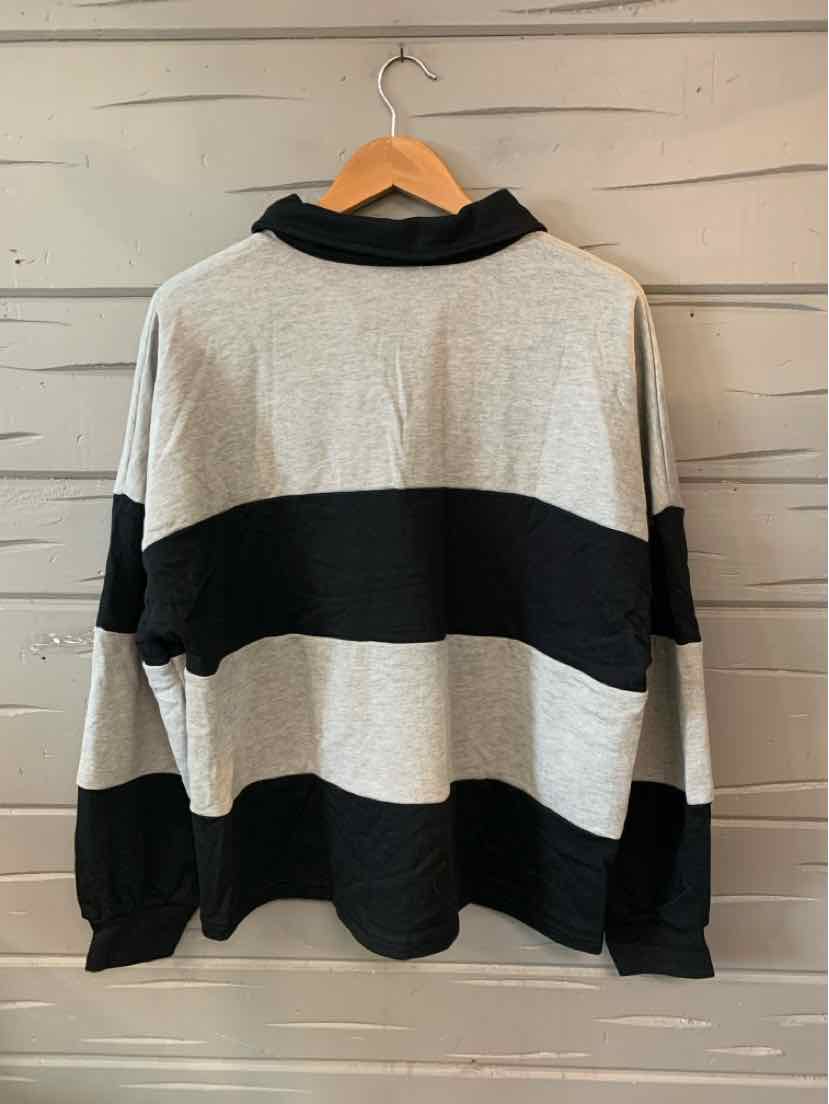Long-sleeve sweater with wide black and gray horizontal stripes and a black collar hanging on wooden hanger.