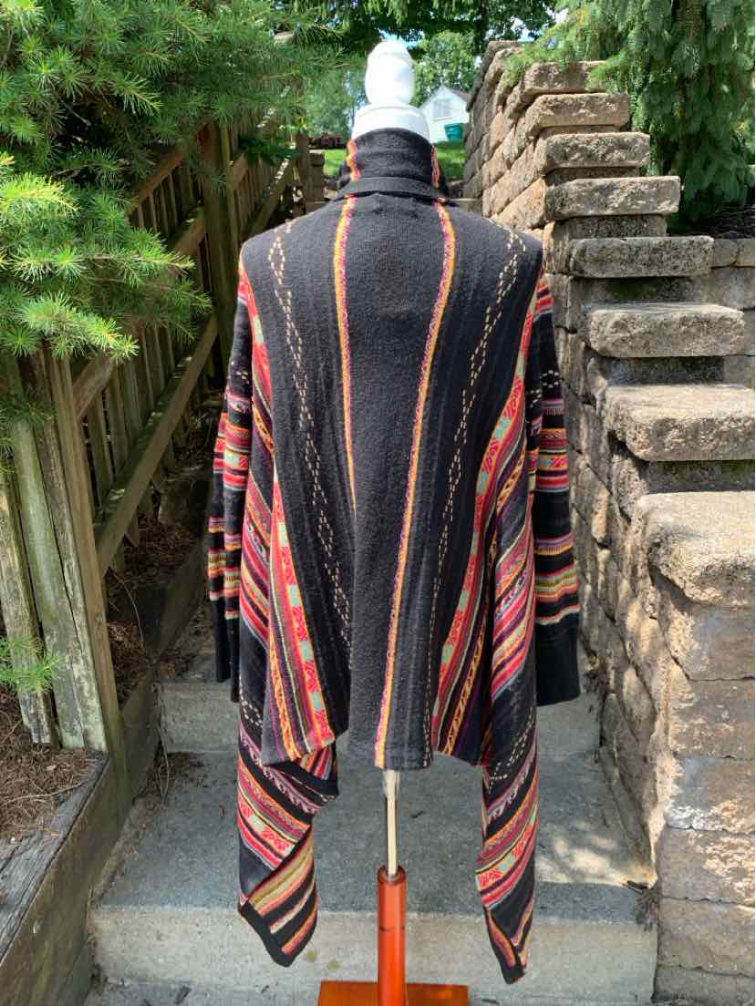 Black and multicolor striped wool poncho with draped sides on a mannequin outdoors.