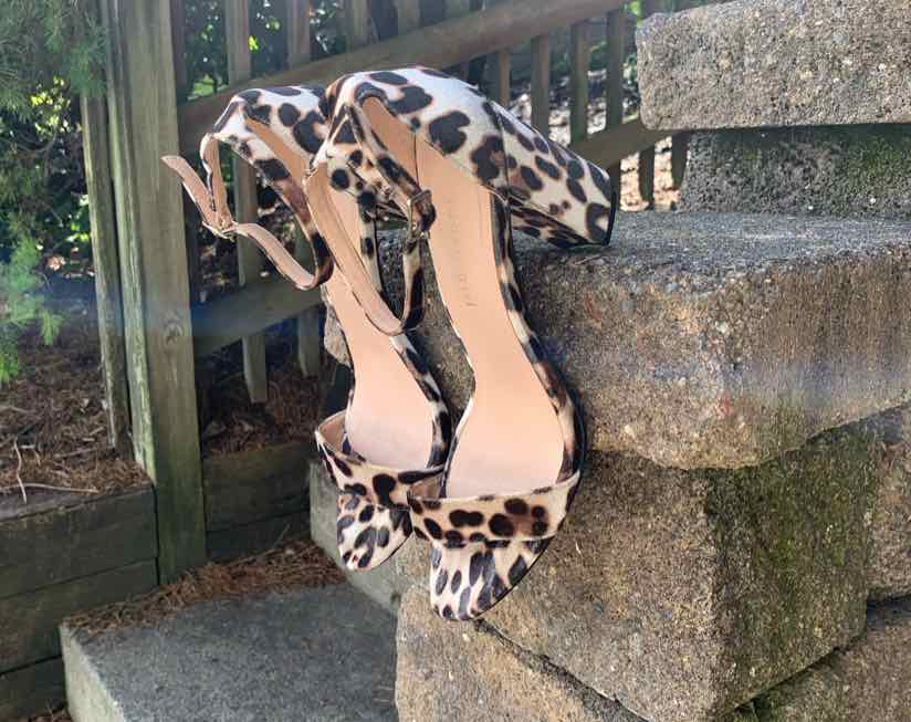 Black and tan cheetah print high-heeled sandals with ankle straps and open toes, size 8.5.