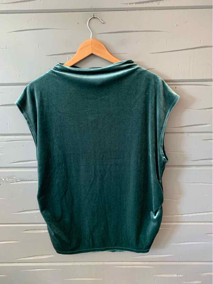 Dark green sleeveless shirt with loose fit and rolled collar on wooden hanger against textured wall.