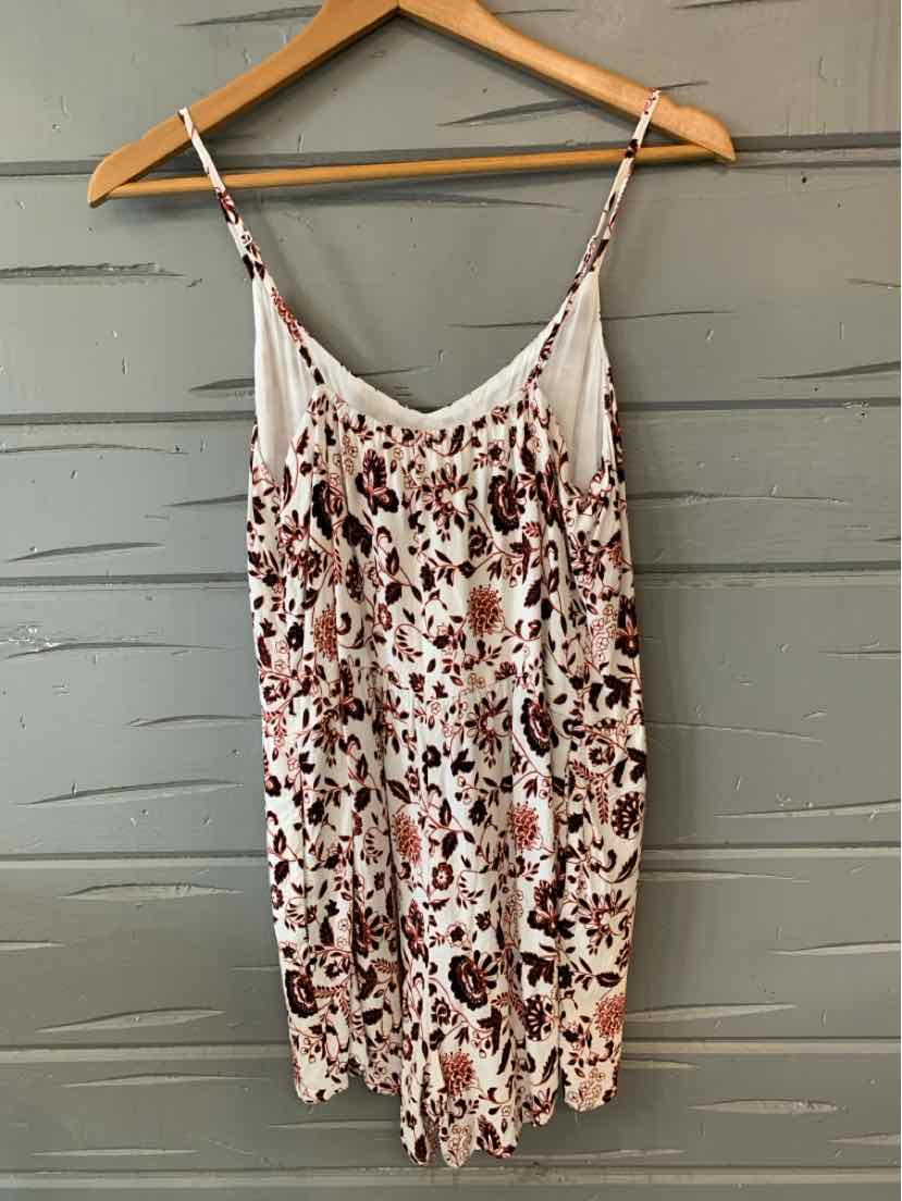 White floral print sleeveless mini dress with adjustable spaghetti straps on wooden hanger.