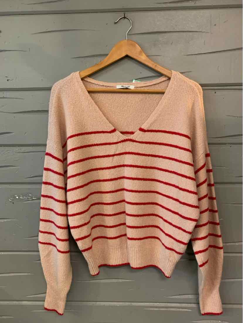 Beige knit sweater with red horizontal stripes and deep V-neck on wooden hanger.