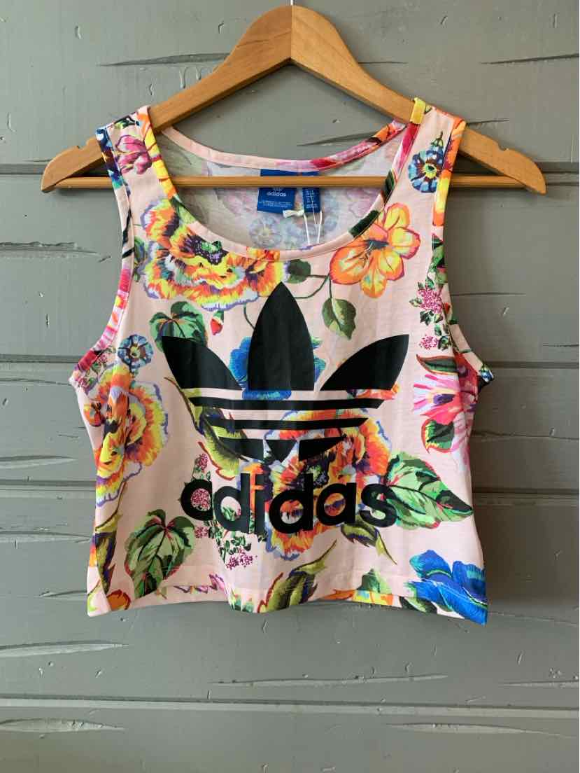 Pink cropped tank top with colorful floral print and large black Adidas logo on front.