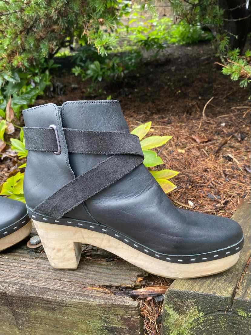 Black leather ankle boot with wooden platform heel and crisscross strap detailing.