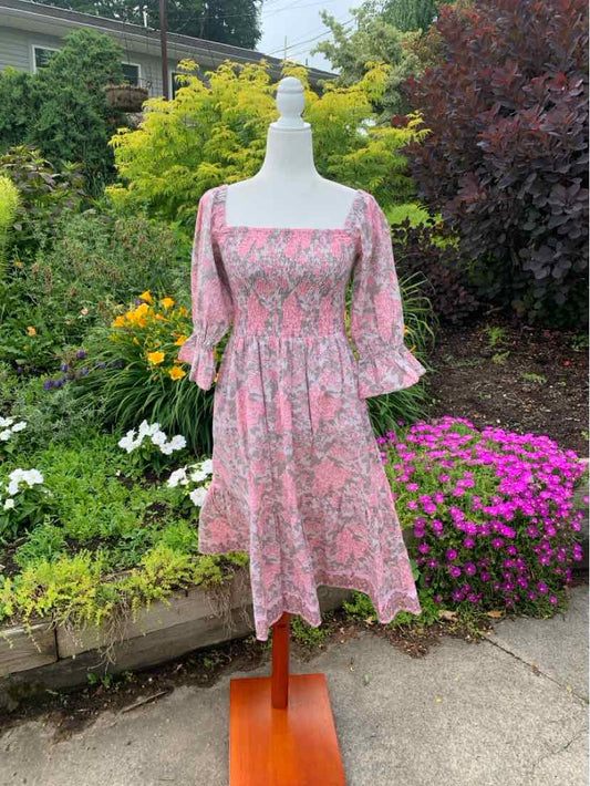 Pink floral knee-length dress with puff sleeves and a square neckline on a mannequin outdoors.