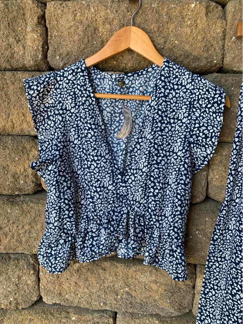 Navy blue floral blouse with white flower pattern, v-neck, short puff sleeves, and gathered waist.