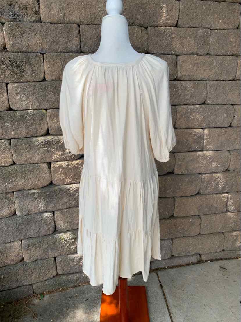 Cream-colored midi dress with puff sleeves and gathered neckline, loose fit with tiered hem.