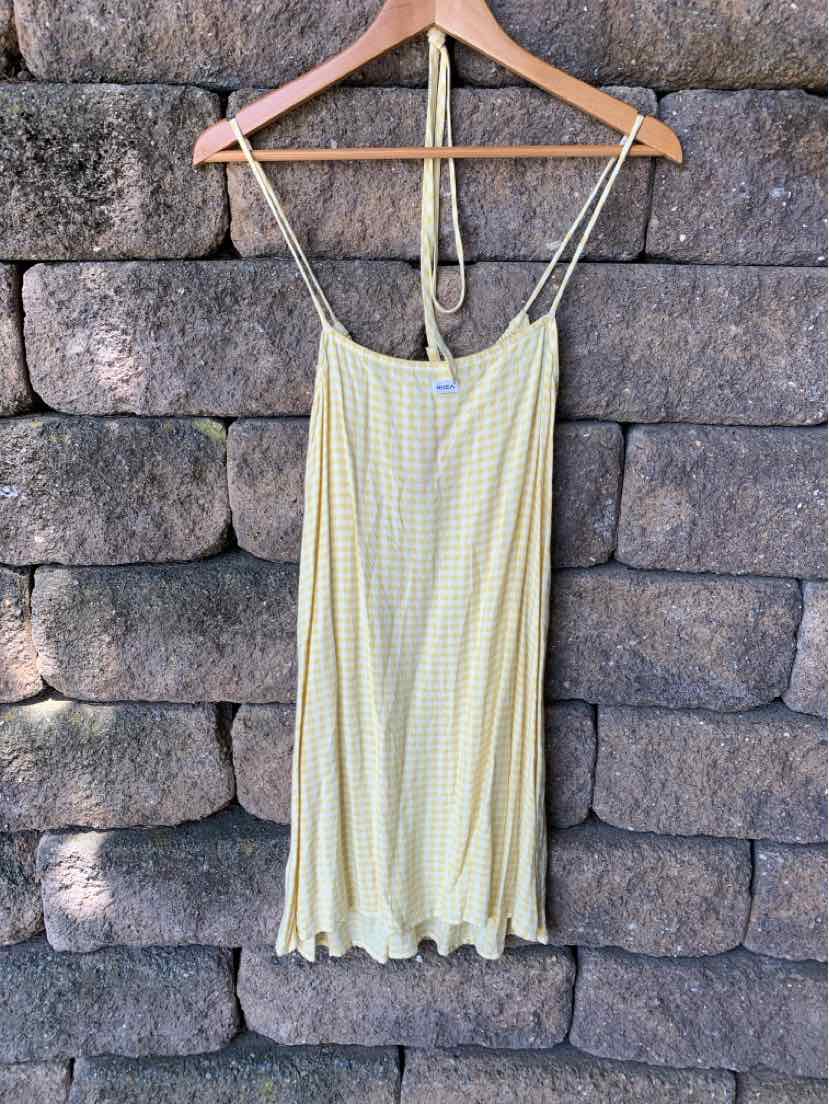 Light yellow gingham slip dress with thin spaghetti straps and ruffled hem hanging on wooden hanger.