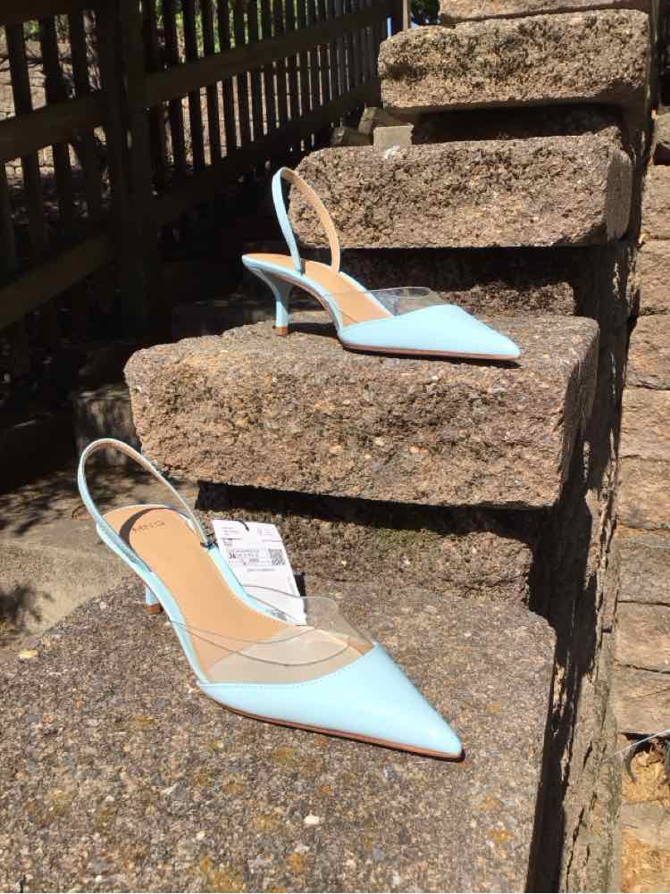 Light blue pointed-toe slingback flats with low heels on outdoor stone steps.