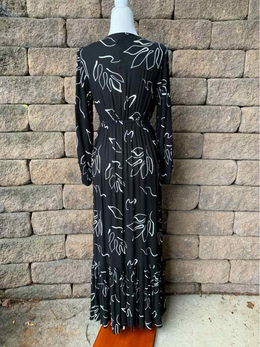 Black long-sleeve maxi dress with white floral outline print and ruffled hem.