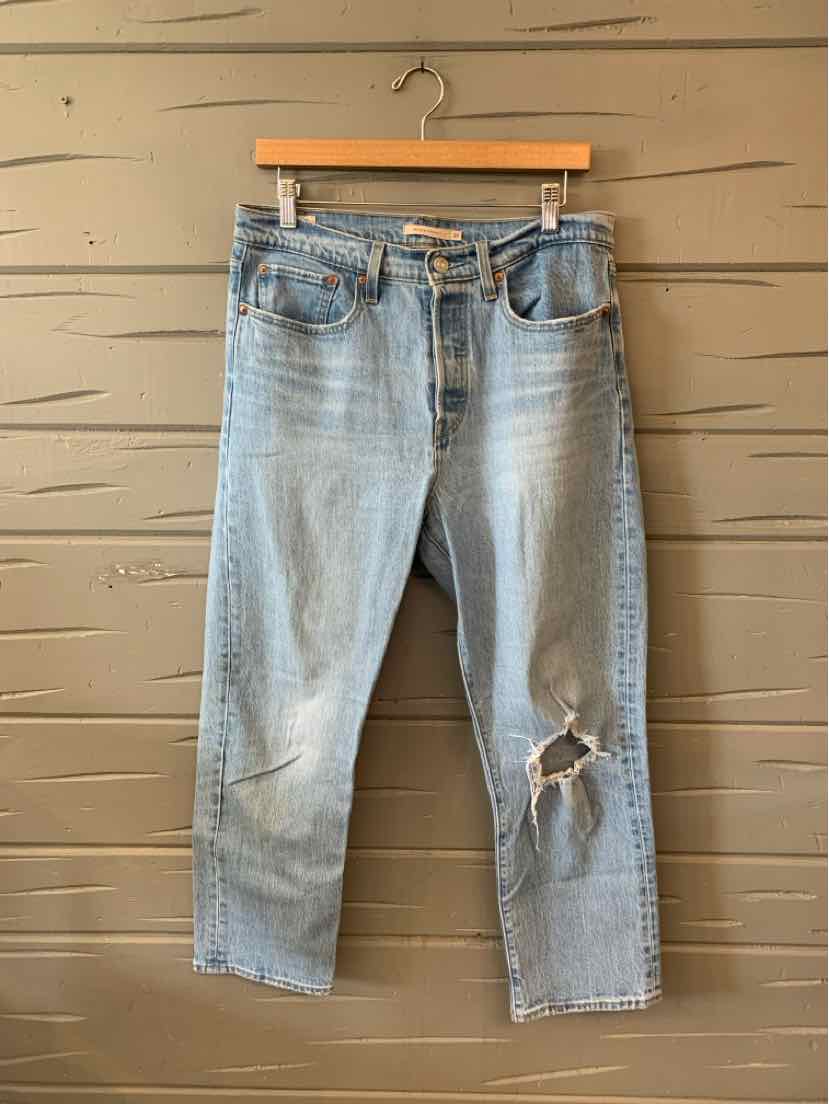 Light blue denim jeans with a relaxed fit, high waist, and a ripped hole above the right knee.