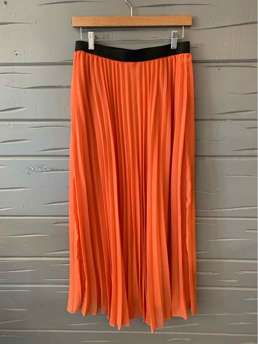 Orange pleated midi skirt with black elastic waistband hanging on wooden hanger.