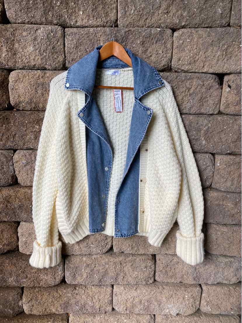 Cream knit cardigan with textured cable pattern, blue denim collar, and snap buttons.