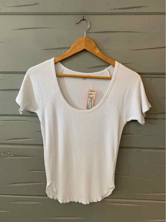 White scoop neck short sleeve T-shirt with fitted silhouette on wooden hanger against gray background.