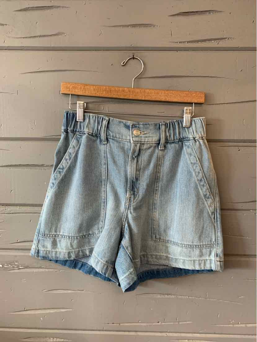 Light blue denim shorts with front pockets, belt loops, and a button closure hanging on wooden hanger.