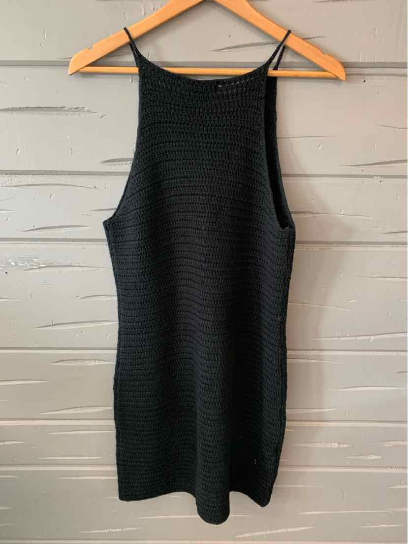 Black sleeveless knit dress with a high neckline and a fitted silhouette hanging on a wooden hanger.