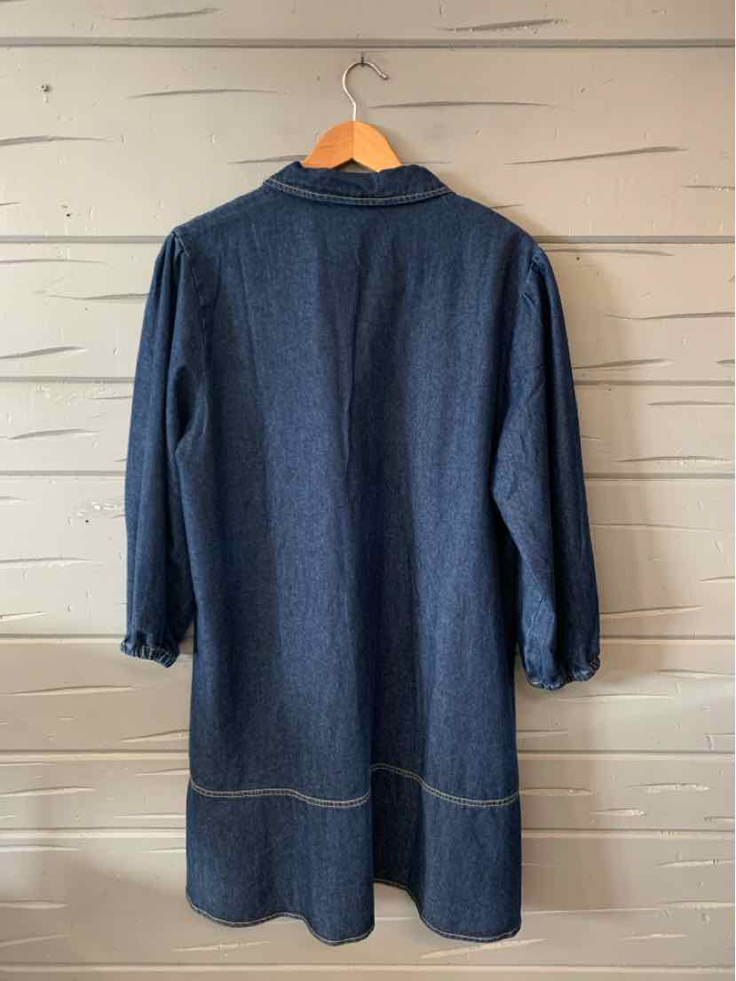 Long navy blue coat with three-quarter sleeves and a straight cut hanging on wooden hanger against light wooden wall.