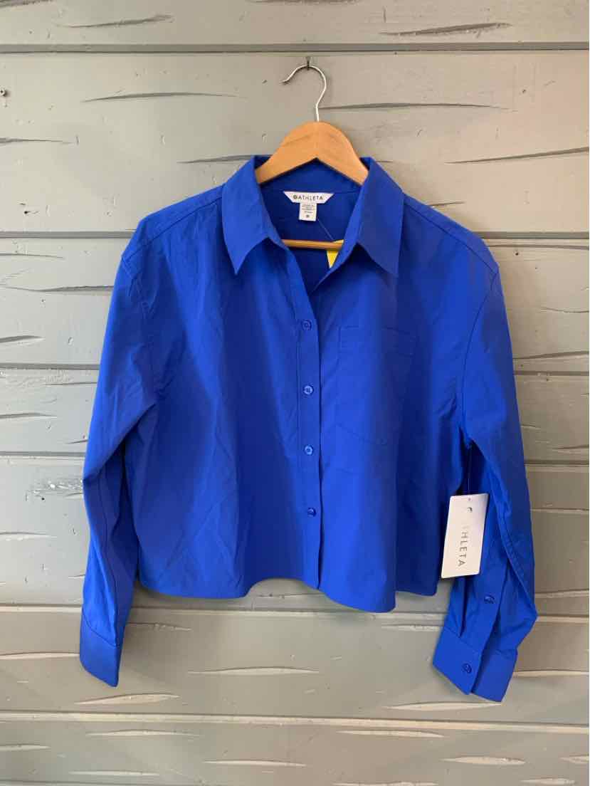 Women's medium blue button-up shirt with pointed collar and long sleeves hanging on wooden hanger.