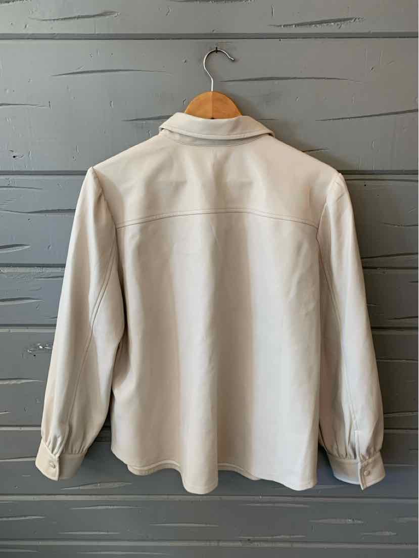Cream-colored faux leather blouse with long sleeves and a relaxed fit, shown from back on wooden hanger.