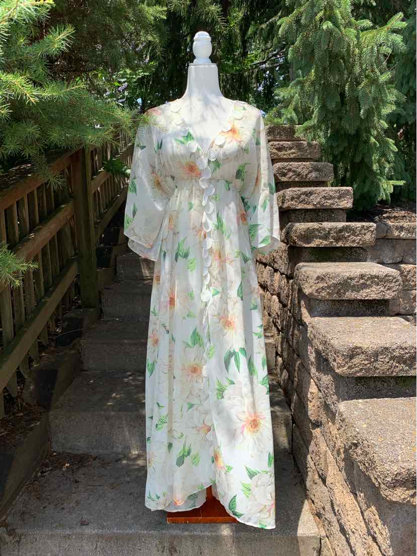 White maxi dress with multicolored floral print, v-neck, long sheer sleeves, and gathered waist.