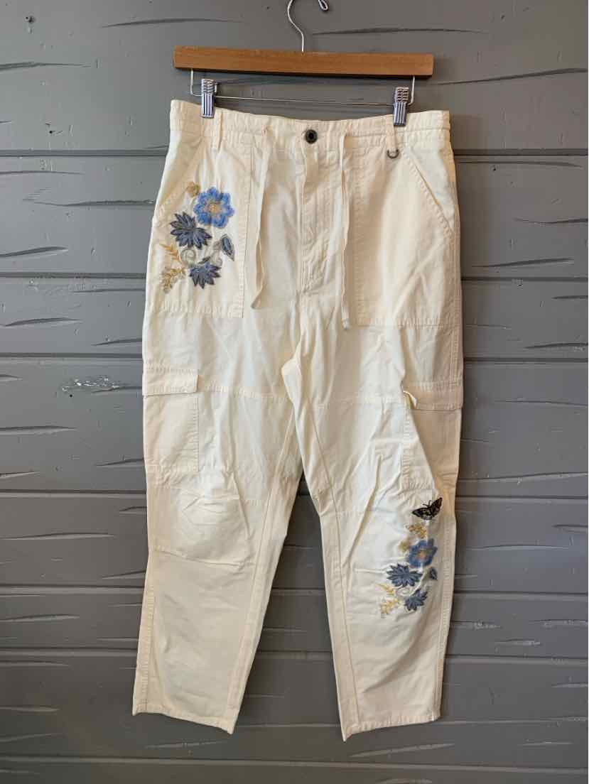 Off-white casual pants with blue floral embroidery on upper left thigh and lower right leg, button and zipper closure.
