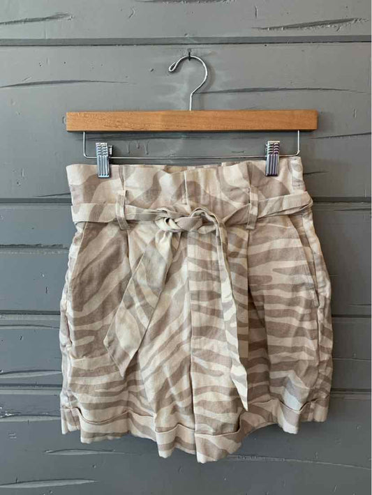 Beige and white zebra stripe high-waist shorts with a fabric belt tied in a bow and front pleats.